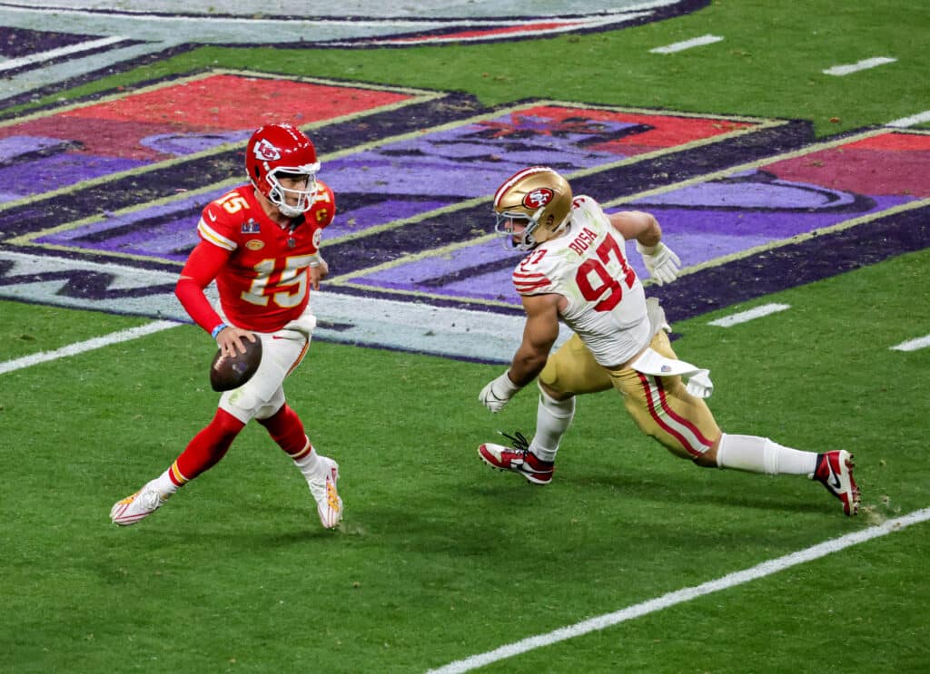 Quarterback Patrick Mahomes of the Kansas City Chiefs looks to throw under pressure from defensive end Nick Bosa of the San Francisco 49ers 